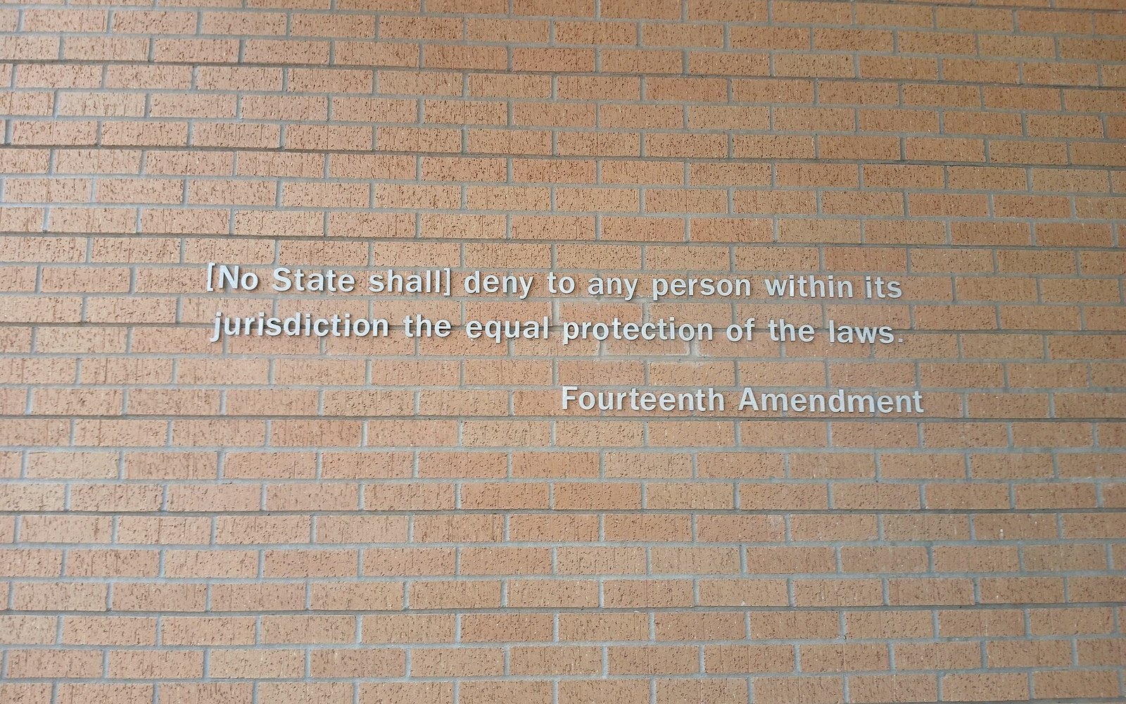 Fourteenth Amendment's equal protection clause inscribed in white letters on a brick wall