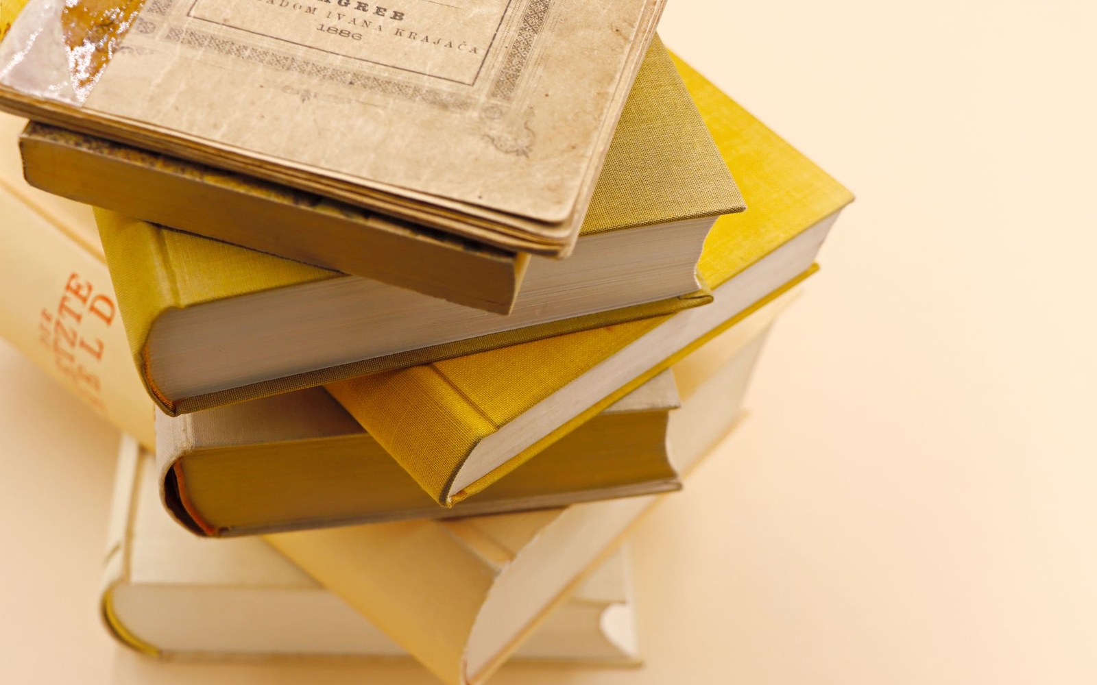 Stack of yellow hardcover books topped with an aged, worn hardcover volume