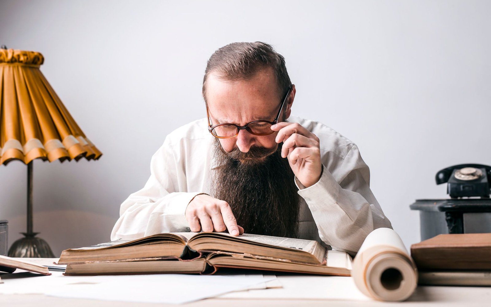 A McGuffey Eclectic Reader open on a wooden school desk, the engravings on the left page visible, a slate and chalk box alongside